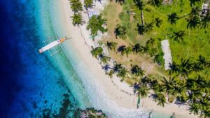Vue aerienne d un ilot borde de cocotiers avec une bangka, region de Caraga