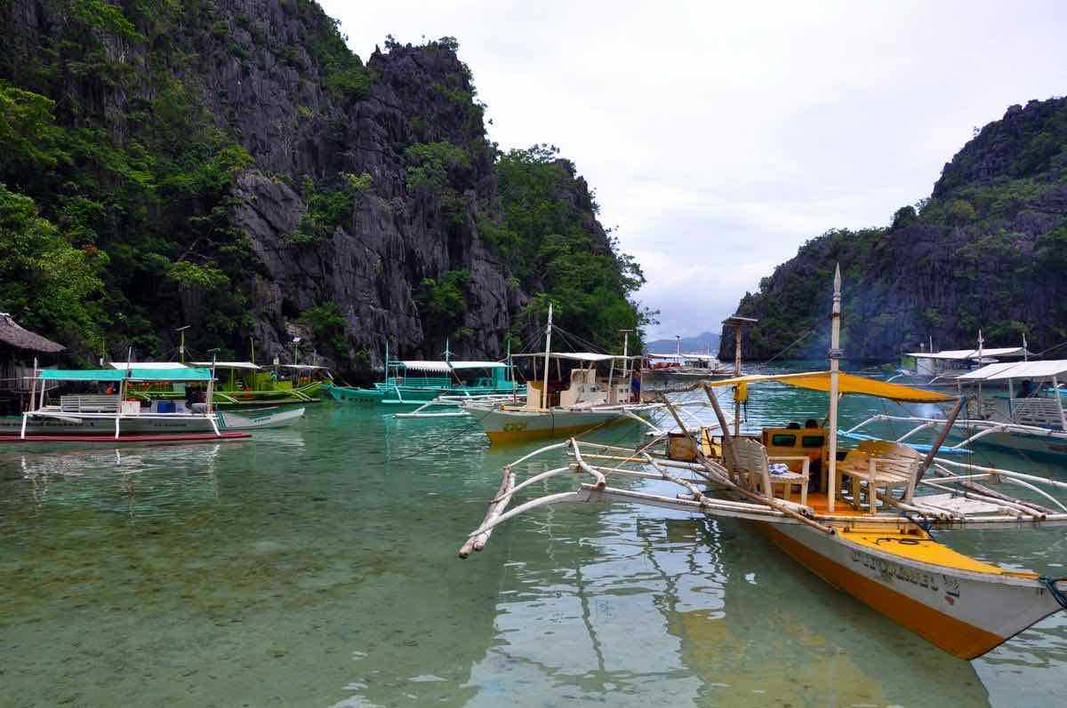Bangkas à balancier amarrées entre les falaises calcaires de la baie de Bacuit, El Nido, Palawan