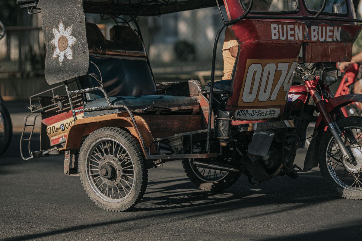 Tricycle philippin, moto avec sidecar couvert, garé dans une rue